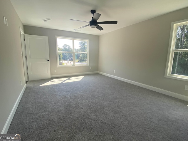 unfurnished bedroom with baseboards, visible vents, dark carpet, and ceiling fan