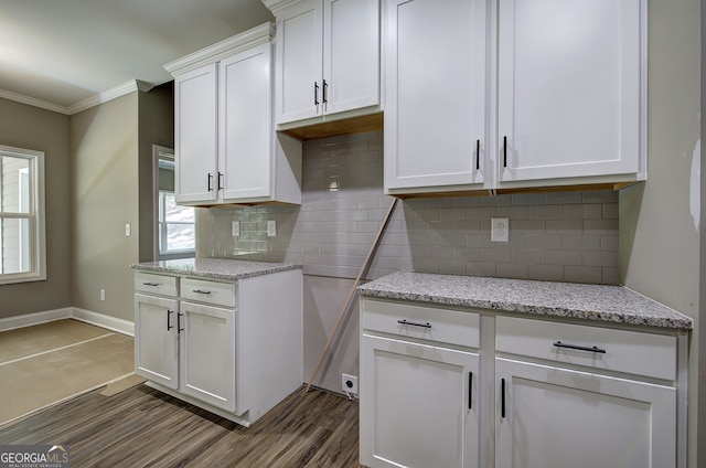 kitchen featuring crown molding, tasteful backsplash, light stone countertops, dark hardwood / wood-style floors, and white cabinets