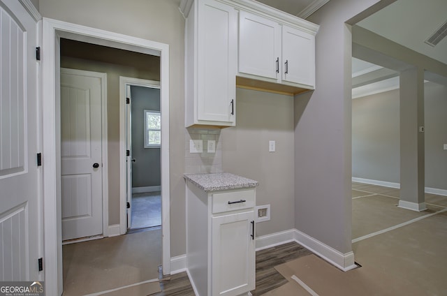 kitchen featuring white cabinetry, light stone counters, and tasteful backsplash