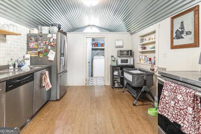 kitchen featuring washer / clothes dryer, stainless steel appliances, sink, lofted ceiling, and light wood-type flooring