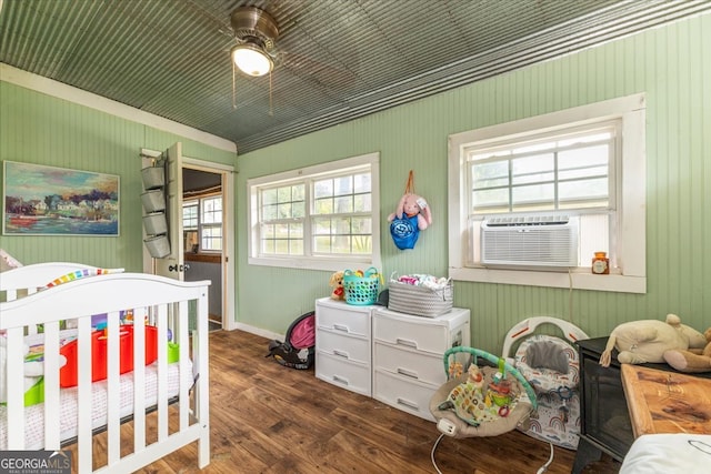 bedroom featuring a crib, dark hardwood / wood-style flooring, cooling unit, and ceiling fan