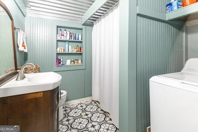 bathroom featuring vanity, washer / dryer, wooden walls, and toilet