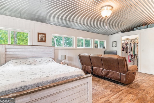 bedroom featuring a closet, a spacious closet, multiple windows, and hardwood / wood-style flooring