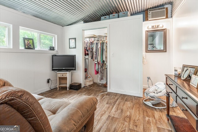 living room with lofted ceiling, light hardwood / wood-style floors, and an AC wall unit