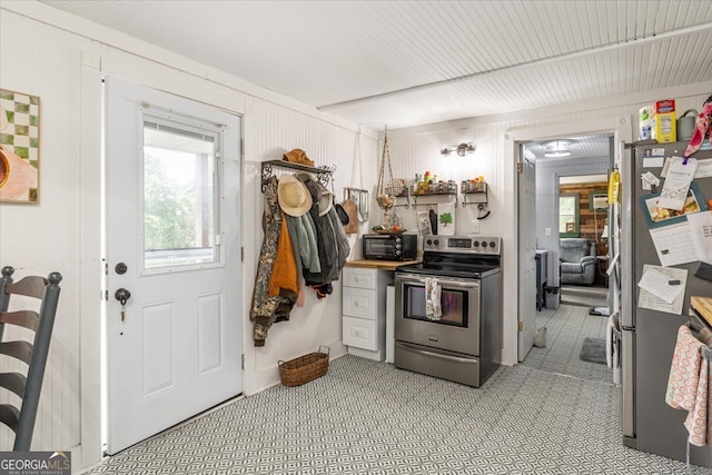 kitchen with appliances with stainless steel finishes and wooden walls