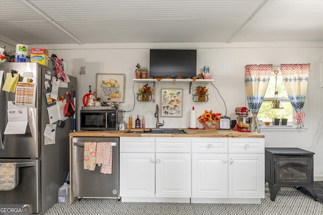 bar featuring butcher block countertops, stainless steel appliances, white cabinetry, and sink