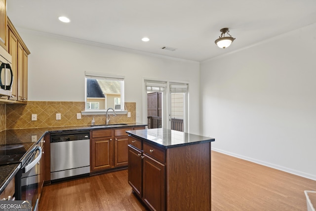 kitchen with sink, stainless steel appliances, tasteful backsplash, hardwood / wood-style floors, and a kitchen island