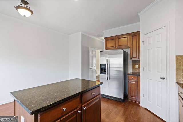 kitchen featuring dark hardwood / wood-style floors, stainless steel refrigerator with ice dispenser, dark stone countertops, decorative backsplash, and a kitchen island