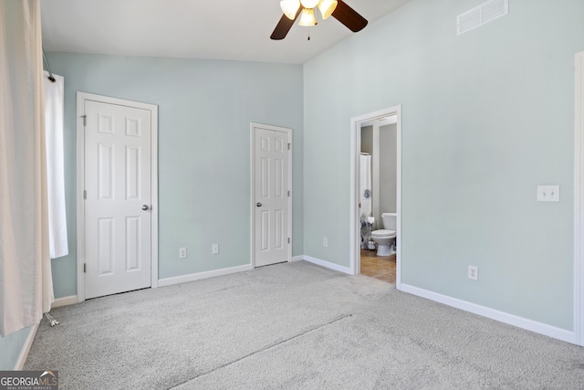 unfurnished bedroom with ceiling fan, light carpet, connected bathroom, and vaulted ceiling