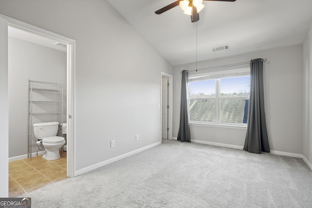 unfurnished bedroom featuring lofted ceiling, light carpet, ensuite bathroom, ceiling fan, and a closet