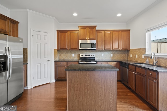 kitchen with tasteful backsplash, ornamental molding, stainless steel appliances, sink, and a center island