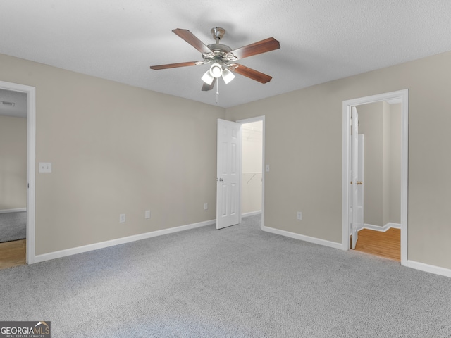 unfurnished bedroom with a textured ceiling, light colored carpet, ceiling fan, and connected bathroom