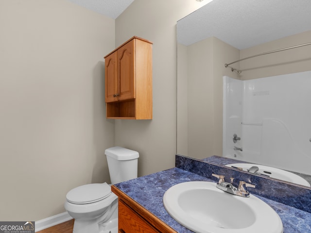 full bathroom featuring hardwood / wood-style floors, toilet, tub / shower combination, vanity, and a textured ceiling