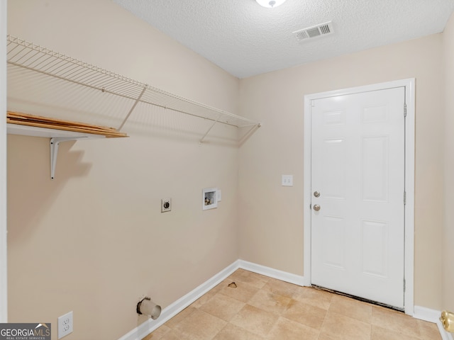 clothes washing area with hookup for a washing machine, electric dryer hookup, and a textured ceiling