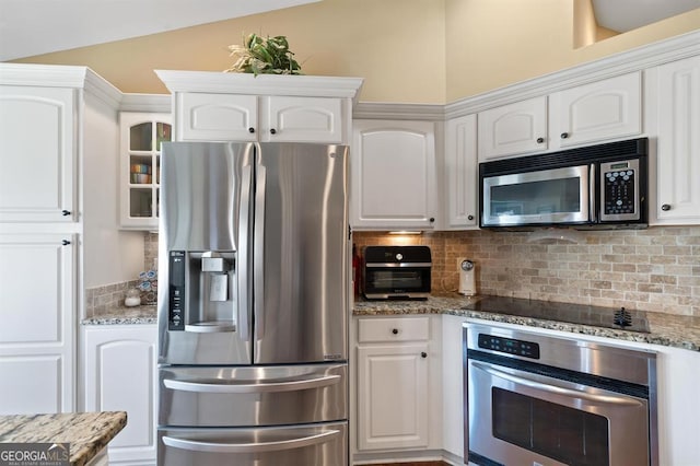 kitchen featuring tasteful backsplash, white cabinets, stone countertops, and appliances with stainless steel finishes