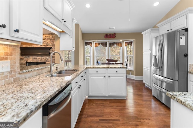 kitchen with kitchen peninsula, sink, white cabinets, and appliances with stainless steel finishes