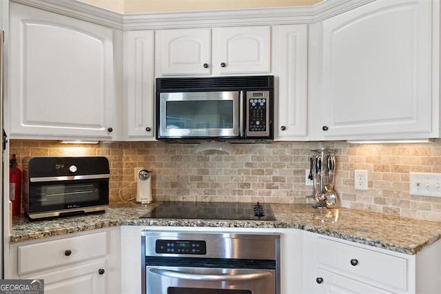 kitchen with backsplash, white cabinets, and appliances with stainless steel finishes