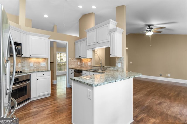 kitchen featuring kitchen peninsula, light stone countertops, stainless steel appliances, white cabinets, and lofted ceiling