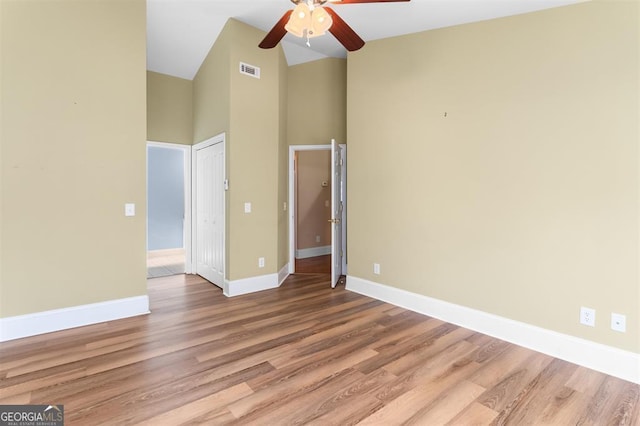 empty room with a high ceiling, light wood-type flooring, and ceiling fan