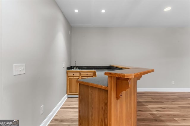 bar featuring light hardwood / wood-style flooring and sink