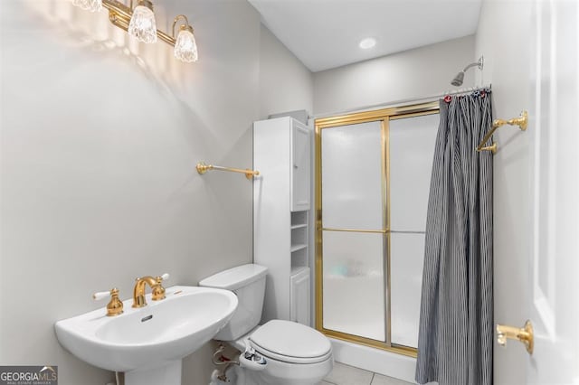 bathroom featuring tile patterned floors, toilet, sink, and walk in shower