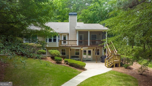 back of property with a sunroom, a yard, and french doors