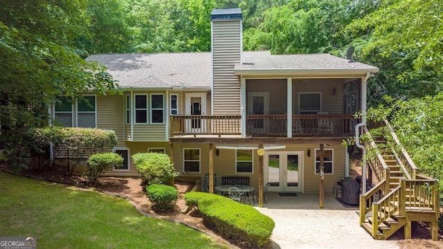 back of house with a sunroom, a patio area, a lawn, and french doors