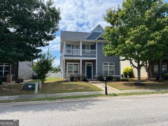 view of front of home with a balcony and a front yard