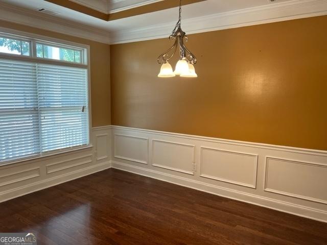 spare room featuring dark wood-type flooring, an inviting chandelier, and ornamental molding