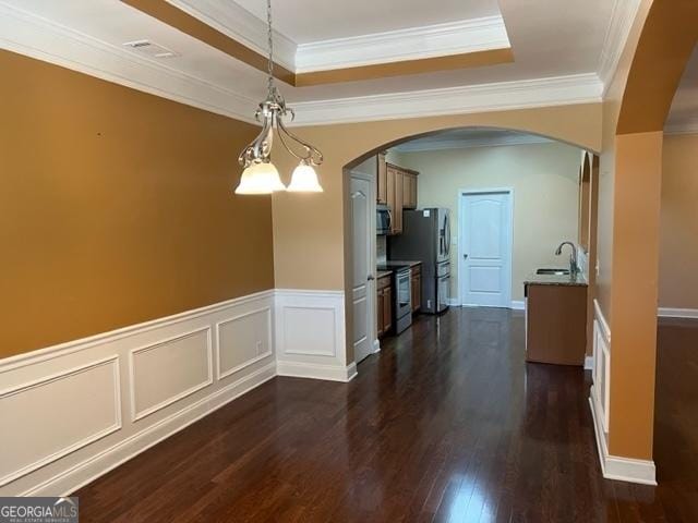 unfurnished dining area with sink, a tray ceiling, ornamental molding, and an inviting chandelier