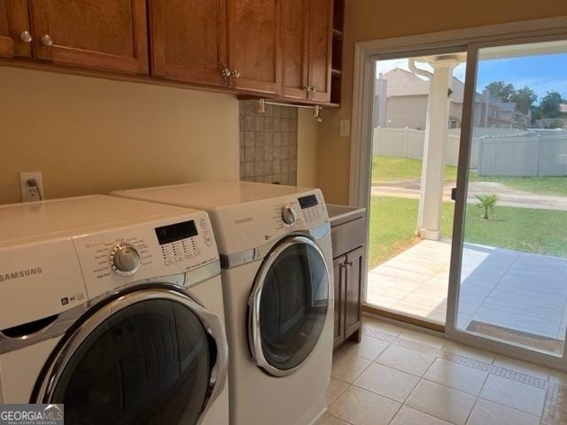 laundry area with cabinets, light tile patterned floors, and washer and clothes dryer