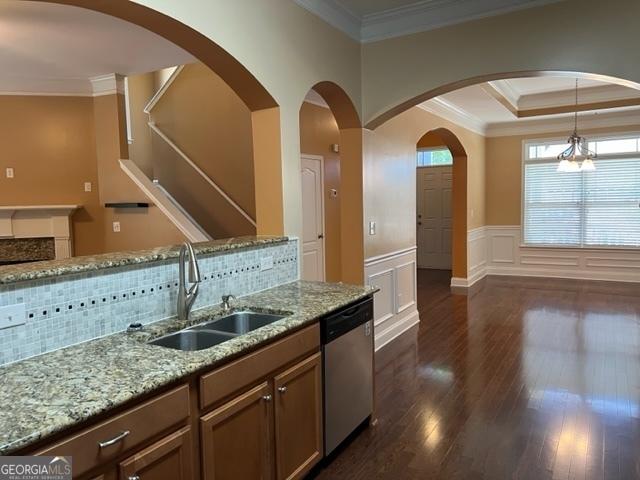 kitchen with dishwasher, sink, hanging light fixtures, ornamental molding, and light stone counters