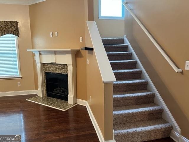 stairway with hardwood / wood-style floors and a fireplace