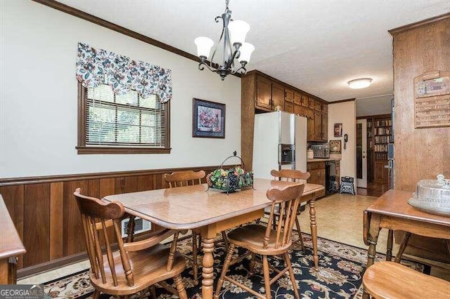 dining area featuring wood walls, a chandelier, and crown molding