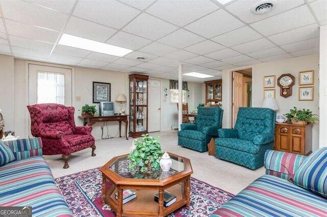 living room featuring carpet flooring and a drop ceiling