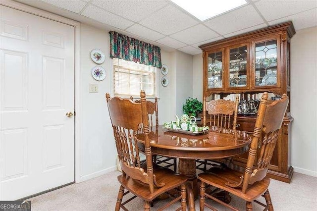 dining space with a paneled ceiling and light colored carpet