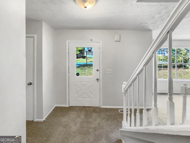 foyer entrance with light colored carpet and a textured ceiling