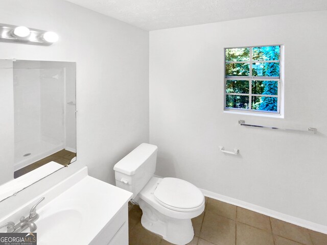 bathroom featuring tile patterned floors, toilet, a textured ceiling, and vanity