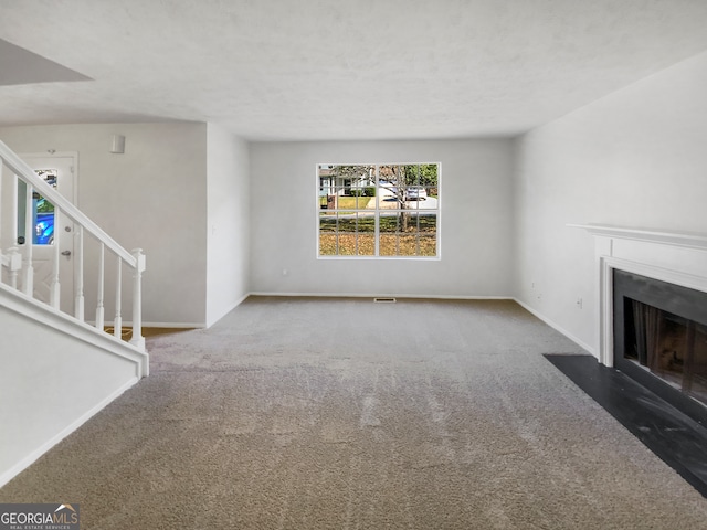 unfurnished living room featuring a textured ceiling and carpet floors