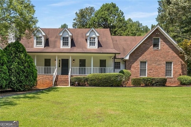 cape cod house featuring brick siding, covered porch, and a front yard