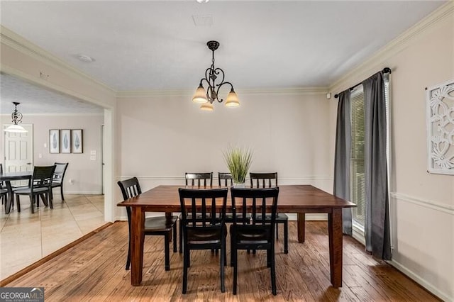 dining space with light wood finished floors, baseboards, crown molding, and an inviting chandelier