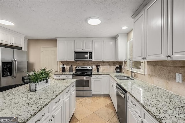 kitchen with tasteful backsplash, appliances with stainless steel finishes, white cabinets, and a sink