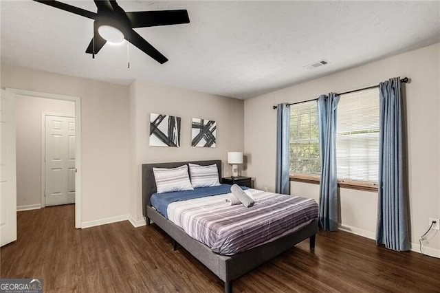 bedroom featuring a ceiling fan, visible vents, baseboards, and wood finished floors