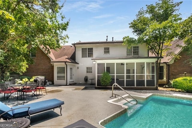 rear view of property featuring an outdoor pool, a sunroom, and a patio