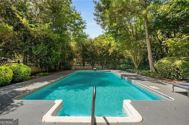 outdoor pool with a patio area and a fenced backyard