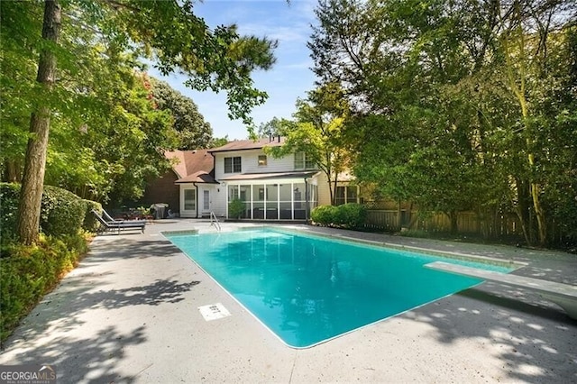 view of pool with a fenced in pool, a patio, a sunroom, fence, and a diving board