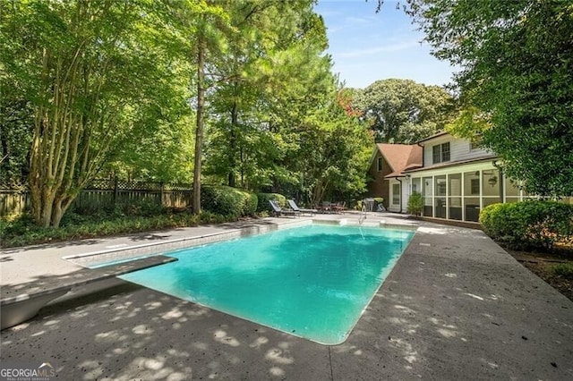 view of swimming pool featuring a patio area, fence, a sunroom, and a fenced in pool