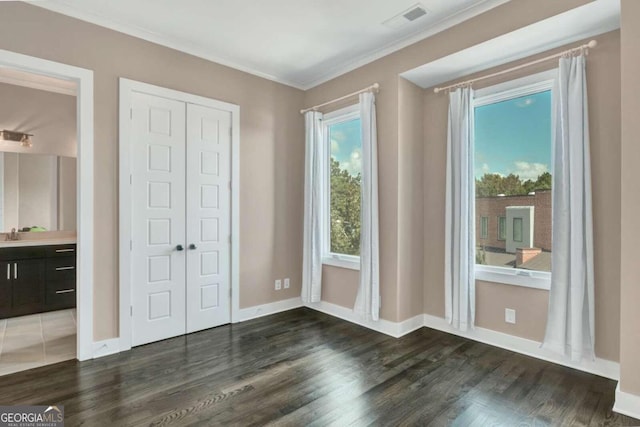 unfurnished bedroom with crown molding, dark hardwood / wood-style flooring, and a closet