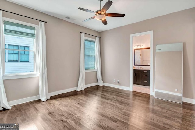 unfurnished bedroom featuring dark hardwood / wood-style floors, ensuite bath, and ceiling fan