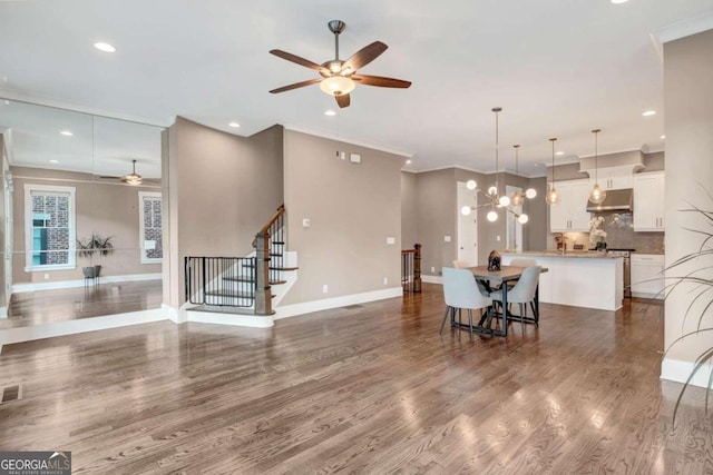 dining room with hardwood / wood-style flooring, ceiling fan with notable chandelier, and crown molding